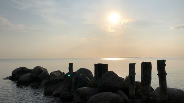 Ostsee im Sonnenaufgang Steine und Pfähle